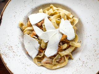 Tagliatelle with mushroom and cheese. White plate. 