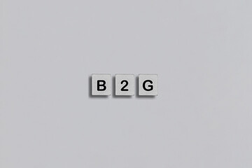 Homemade wooden tile with B2G abbreviation - business to government a process of sale and marketing of goods and services to federal, state, or local agencies on a grey background