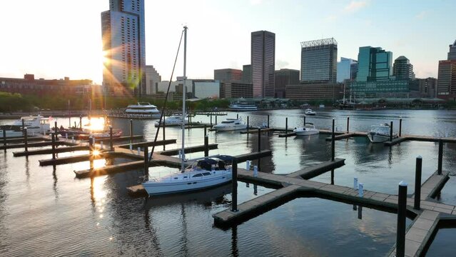 Quiet evening sunset with sailboat in Baltimore Maryland Inner Harbor. City skyline at night. Aerial approach.