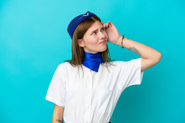 Airplane stewardess English woman isolated on blue background having doubts and with confuse face expression