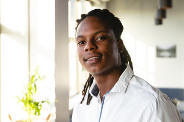 Portrait of confident african american young businessman with dreadlocks in creative office