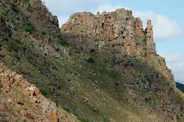 Sharp grassy mountains against a blue sky with  clouds along the road near the city of Erzurum, Eastern Anatolia region, Turkey