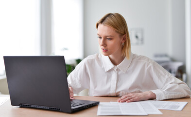 Fototapeta premium Young woman working on laptop in living room.