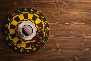 Cup of coffee on dart board on brown wooden table background. Composition with free space for text or design