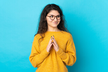 Teenager Russian girl isolated on blue background scheming something