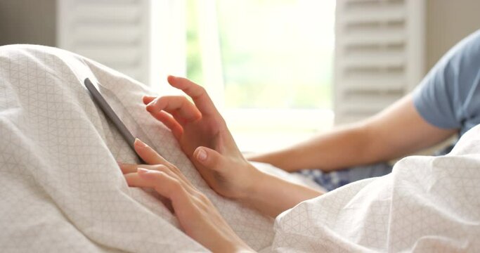 A couple sitting in bed using their digital tablet together