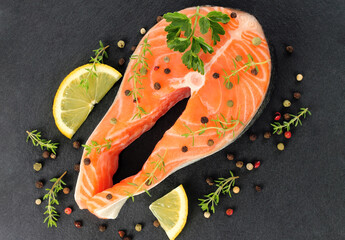 Fresh raw Salmon fish steak whith spices and lemon, top view, on black background