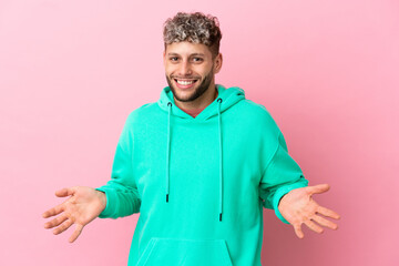 Young handsome caucasian man isolated on pink background happy and smiling