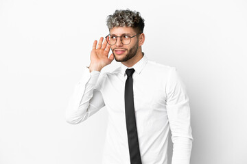 Business caucasian man isolated on white background listening to something by putting hand on the ear