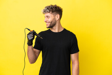 Tattoo artist caucasian man isolated on yellow background looking side