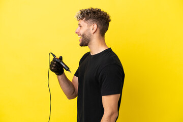 Tattoo artist caucasian man isolated on yellow background laughing in lateral position
