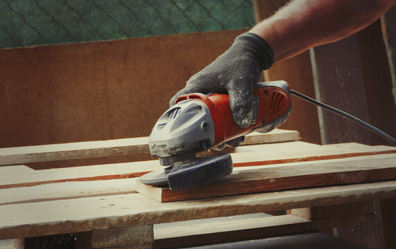 Close-up shot of a man sanding a wood board with an angle grinder at workshop, woodworking scene - Powered by Adobe