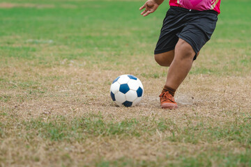 Football soccer children training class. Kindergarten and elementary school kids playing football in a field. Group of boys running and kicking soccer on sports grass pitch. Selective focus on ball.