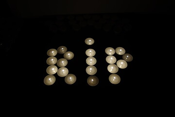 rip rest in peace written with burning candles isolated on black background