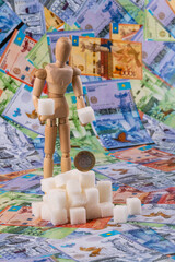 Pieces of refined sugar, a figurine of a man and Kazakhstani money