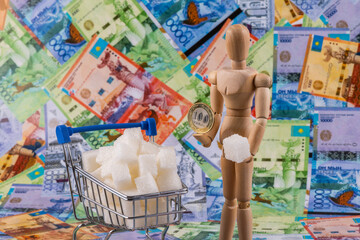 Pieces of refined sugar in a miniature shopping cart from a supermarket, a human figurine and...