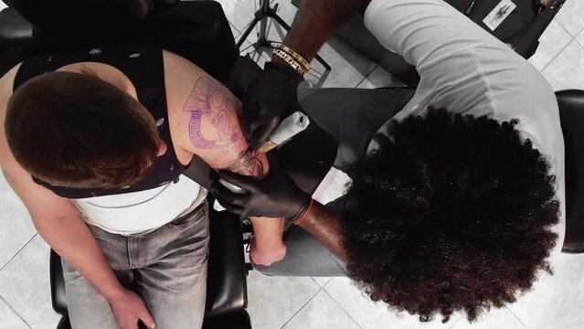 Tattoo master makes a tattoo on a man body. View from above. High quality 4k footage