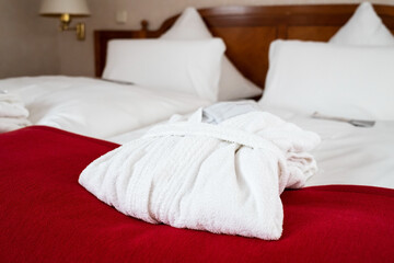 White bathrobe on a bed in a hotel room.