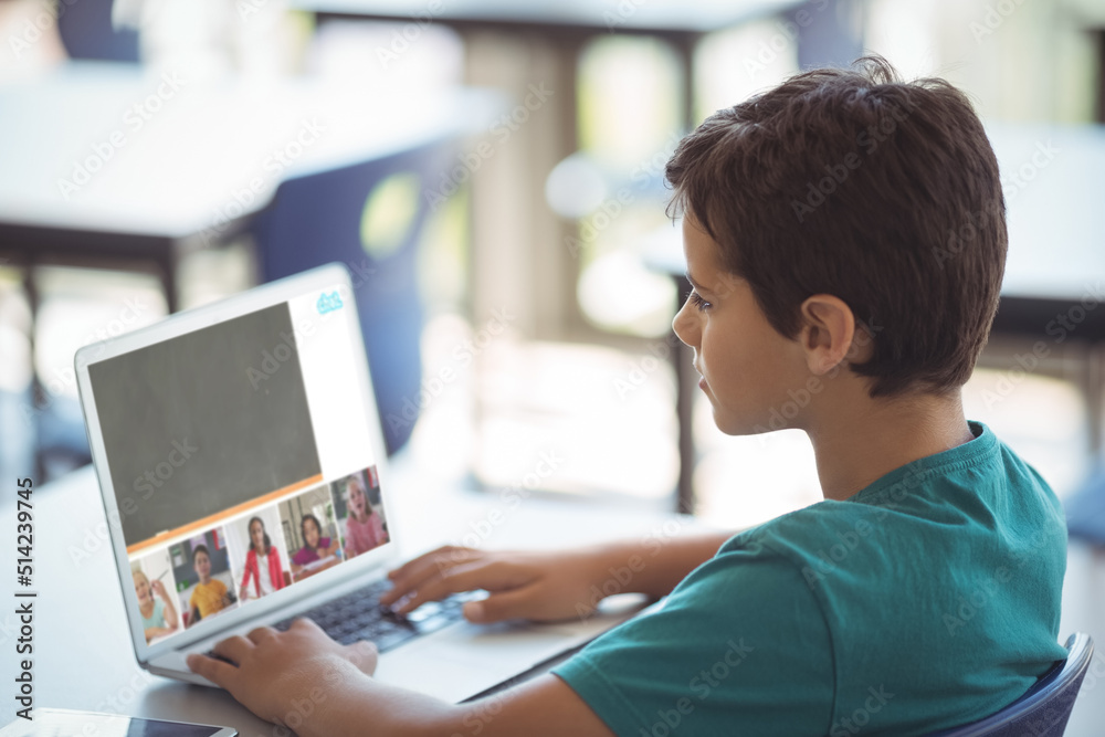 Poster Side view of caucasian boy studying online through video call on laptop while sitting at table