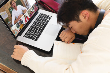 Hoge hoekmening van Aziatische tiener die voor laptop slaapt tijdens online lezing thuis