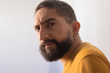 portrait of serious latin man in yellow shirt on white background