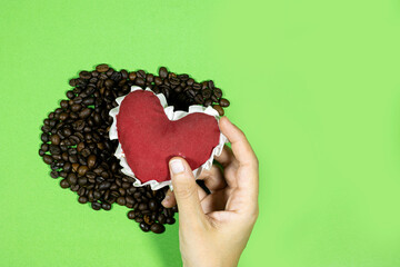 hand hold red heart with Roasted coffee beans on wood table, love coffee concept