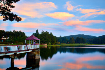 Fototapeta premium beutiful landscape at sunset with clouds of colors and lake with reflections like mirror and structure in the water from presa brockman el oro de hidalgo state of mexico
