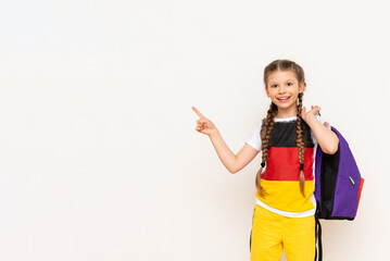 The flag of Germany on the T-shirt of a little girl. A beautiful child with pigtails points with...