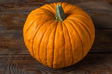Beautiful huge pumpkin on a dark brown wooden table. View from above. Isolated pumpkin.
