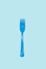 Un tenedor azul sobre un fondo celeste liso y aislado. Vista superior y de cerca. Copy space
