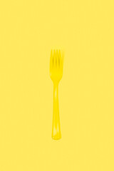 Un tenedor amarillo sobre un fondo amarillo liso y aislado. Vista superior y de cerca. Copy space