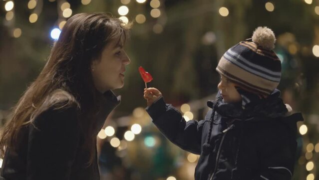 Sweet toddler child  and mother eat together heart shape lollipop, Christmas