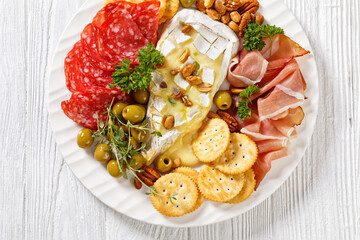 savory baked brie with crackers, salami, nuts, ham