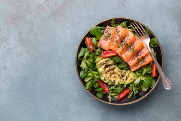 Salmon fish fillet with fresh salad, avocado top view.