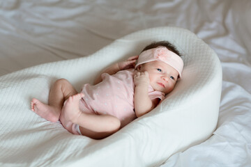 Cute newborn baby lying in white cocoon on bed. Baby goods packaging template. Healthy and medical concept. Copy space