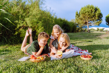 The family is having a picnic and looking at the smartphone.
