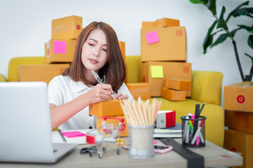 good looking asian woman Checking stock, preparing to pack items to be sent to customers. A lot with tabrets, concepts, online business online products work from home sme