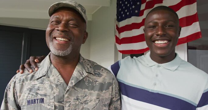 Video of happy african american senior soldier and his son looking at camera