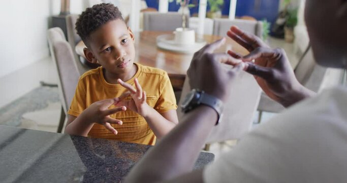 Video of happy african american father and son having fun at home, playing finger games