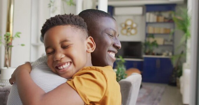 Video of happy african american father and son hugging at home