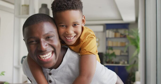Video of happy african american father and son hugging at home