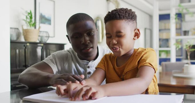 Video of african american father helping blind son reading in braille
