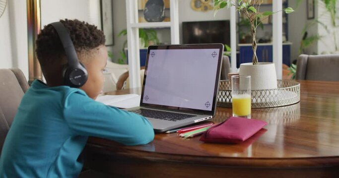 Video of african american boy in headphones learning with laptop with copy space