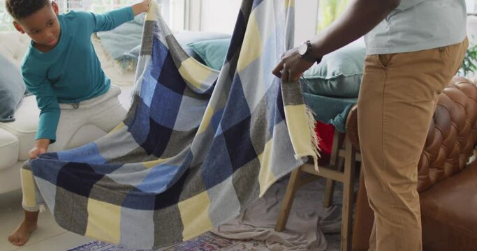 Video of midsection of african american father and son preparing base from chairs and blanket