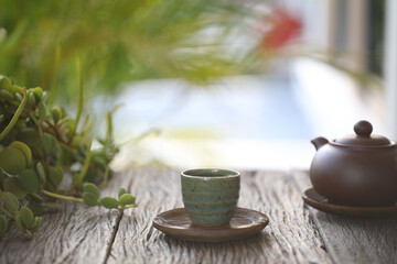 earthenware teapot and green small tea cup and on wooden table