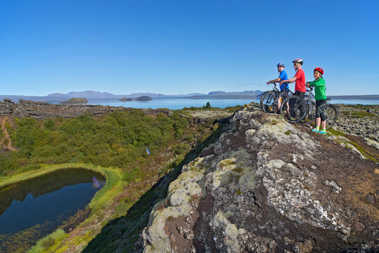 three friends exploring a volcanic crater on their mountain bikes