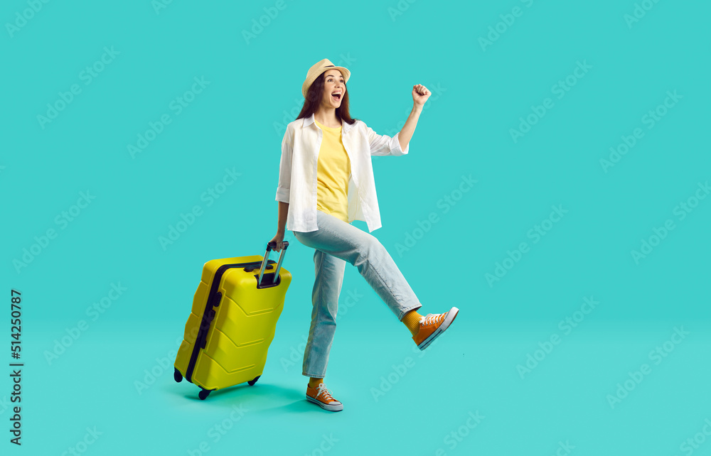 Wall mural happy woman with yellow suitcase going on summer holiday. smiling overjoyed young girl wearing jeans