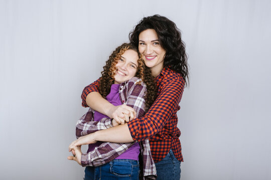 Portrait of happy mom and teeneger daughter spend time together. Teenage girl hugging her mother