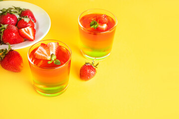 Glasses of tasty summer dessert layered colorful jelly with fresh strawberries