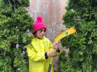 a thoughtful child with face painting between two  christmas trees .shabby brown wall